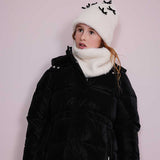Giacca imbottita lunga nera con zip indossata da bambina con cappello e scaldacollo bianco